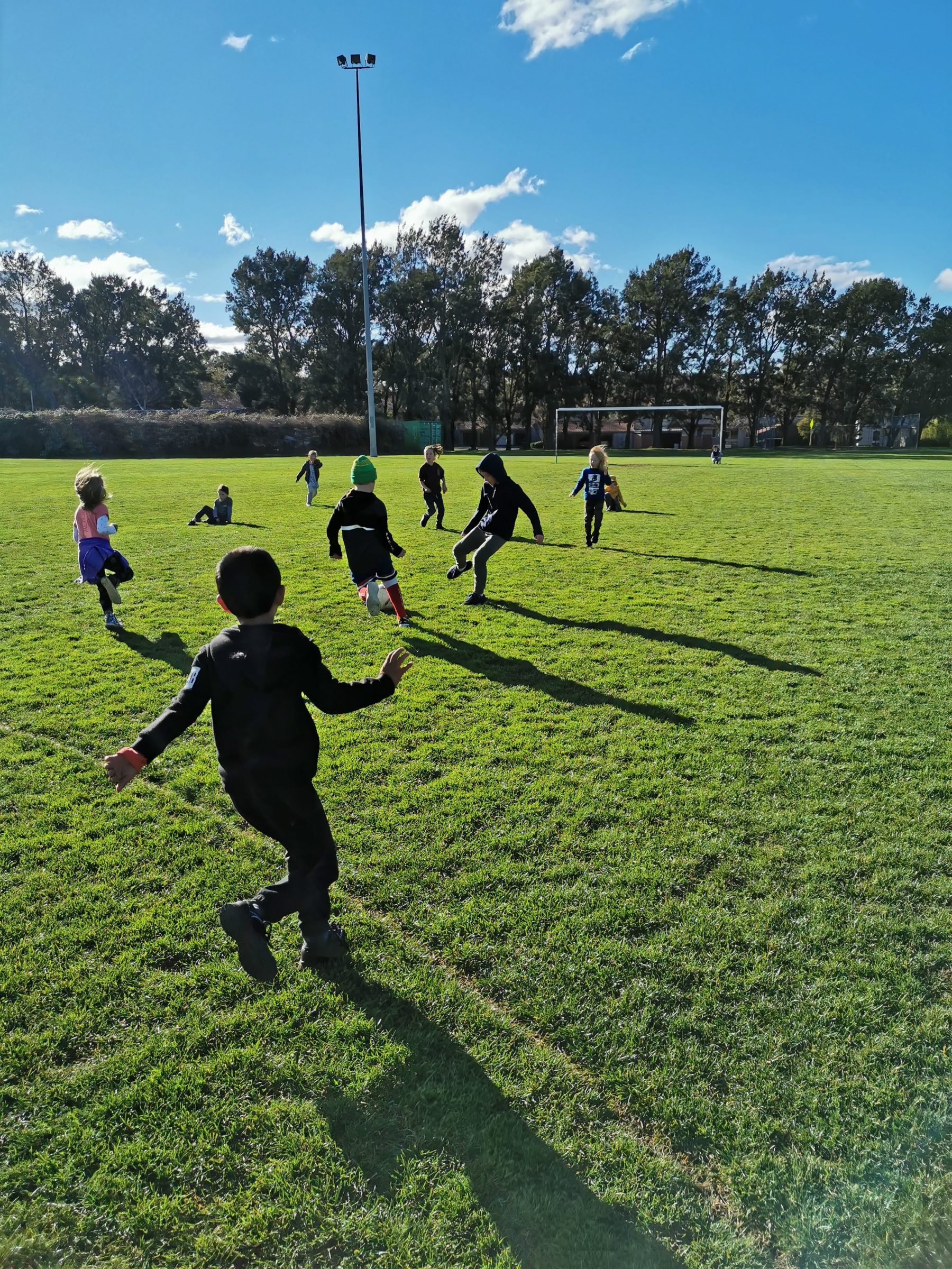 preschoolers playing soccer on oval