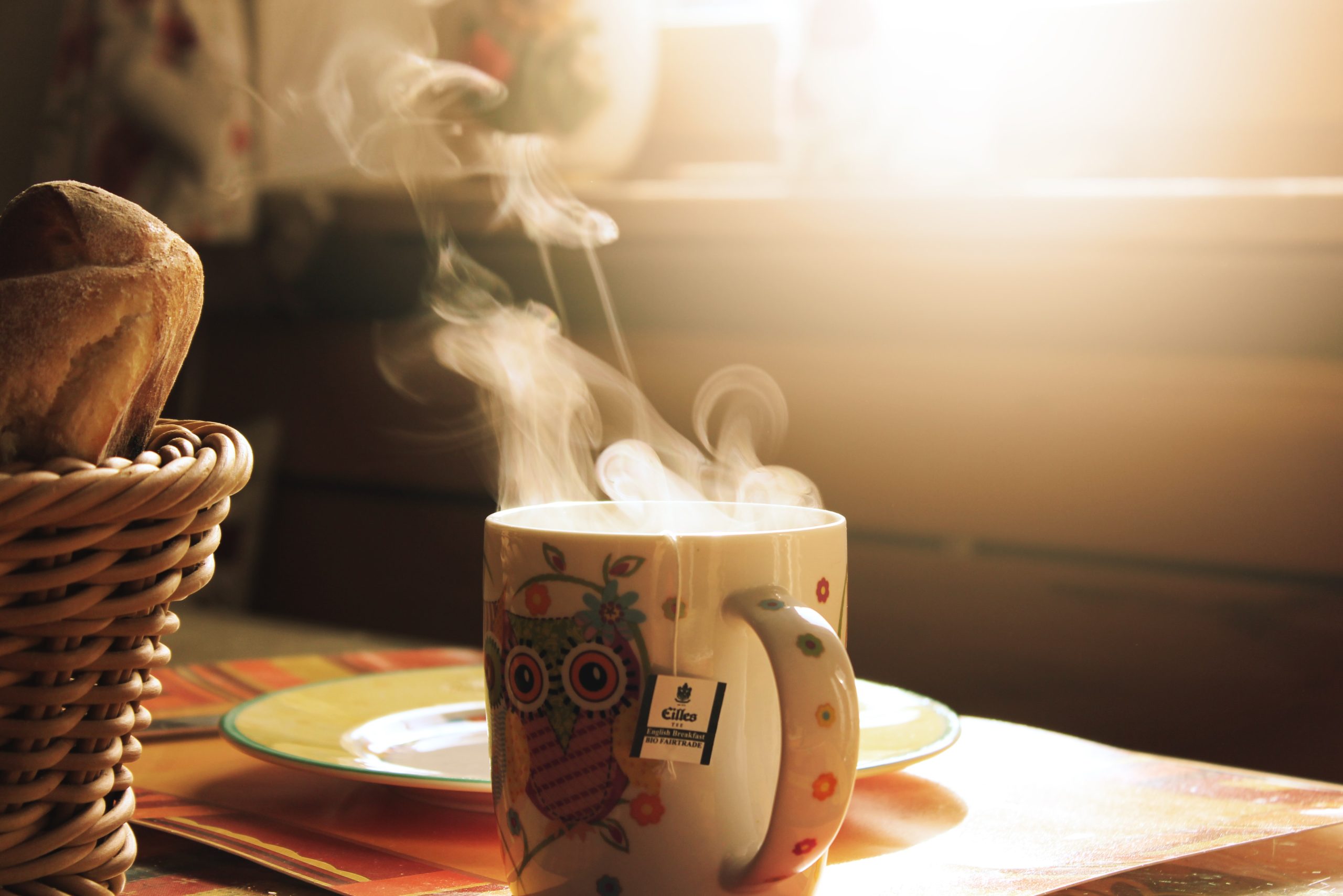 mug with tea on a table with sunlight shining through the window and steam rising from the mug